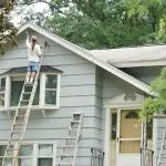 Home exterior being painted on a ladder during mild weather, illustrating the best time for exterior painting in Warwick NY