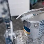 Paint can and brush on a ladder, representing the questions homeowners ask before hiring an exterior painting company.