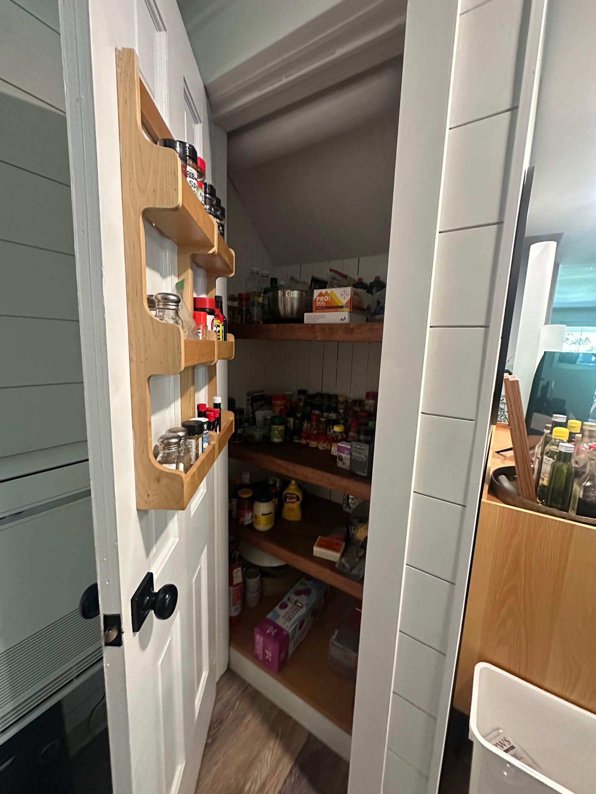 Custom white shiplap pantry with wooden shelving and door-mounted spice rack installed by Willow Tree Painting & Home Improvement