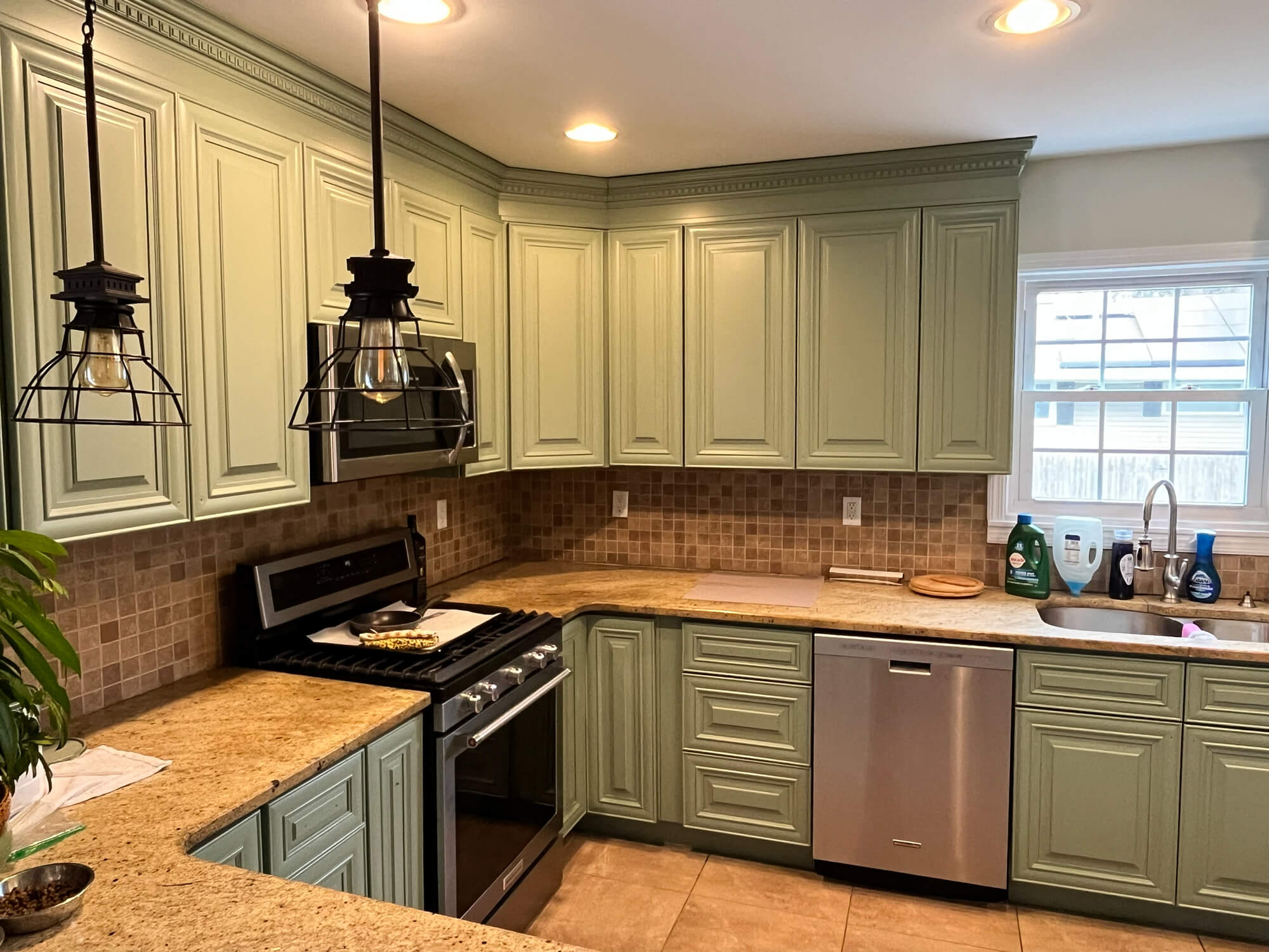 Luxury kitchen cabinet refinishing project featuring sage green painted cabinets, granite countertops, and modern stainless steel appliances, expertly completed by Willow Tree Painting & Home Improvement.