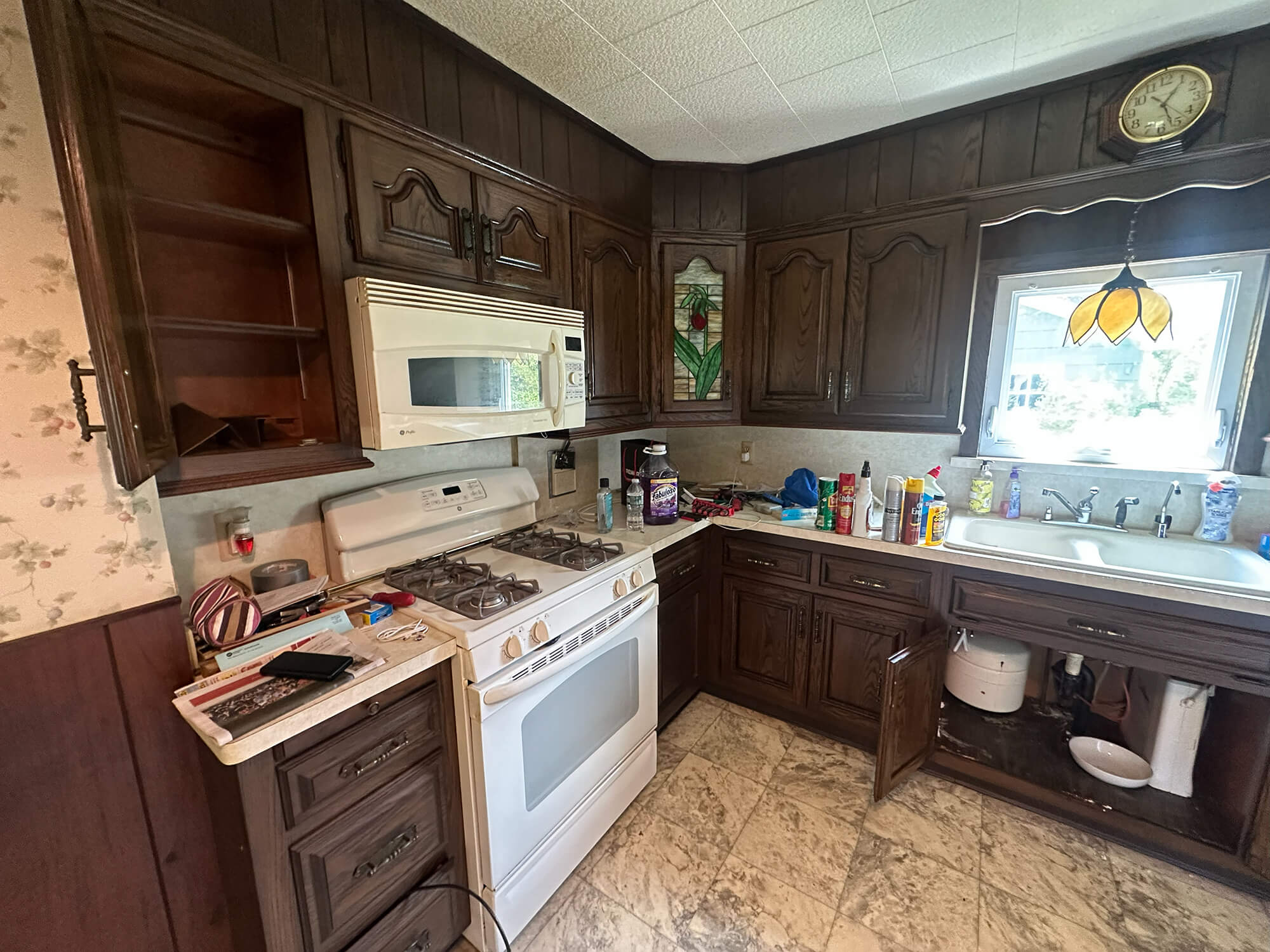 kitchen cabinet refinishing project displaying outdated dark cabinets and paneling before renovation.