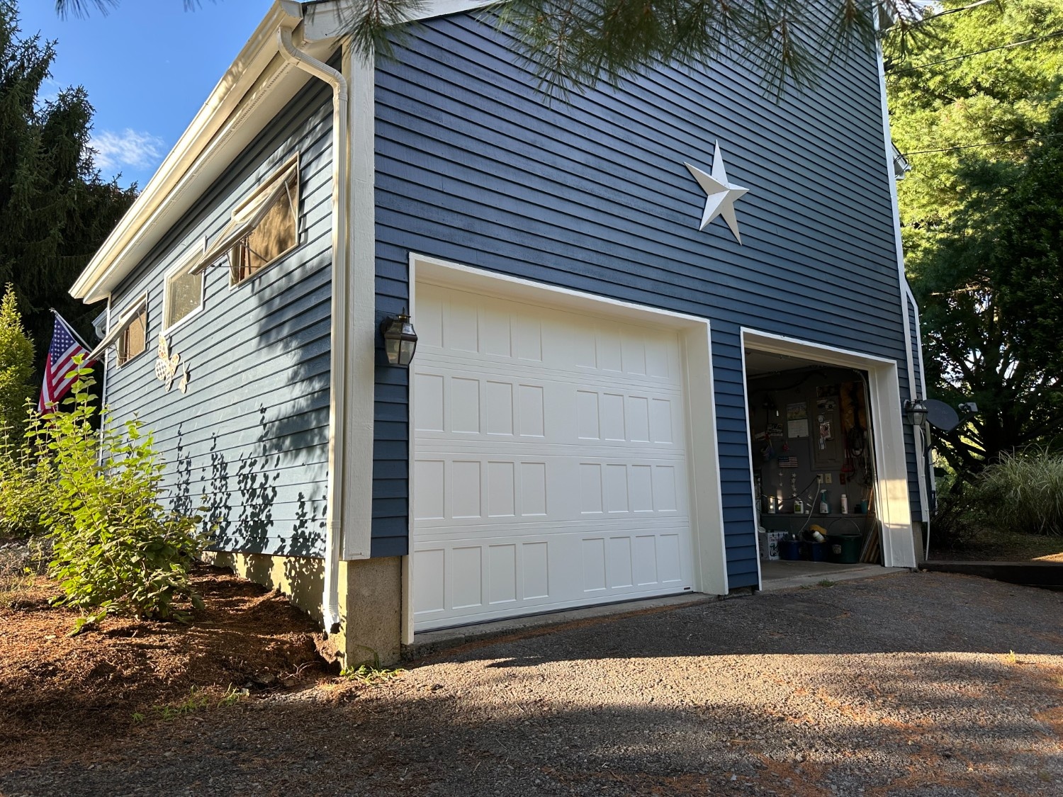 Professional Exterior Painting of a two-story garage with navy blue siding, crisp white trim, and a white paneled door.