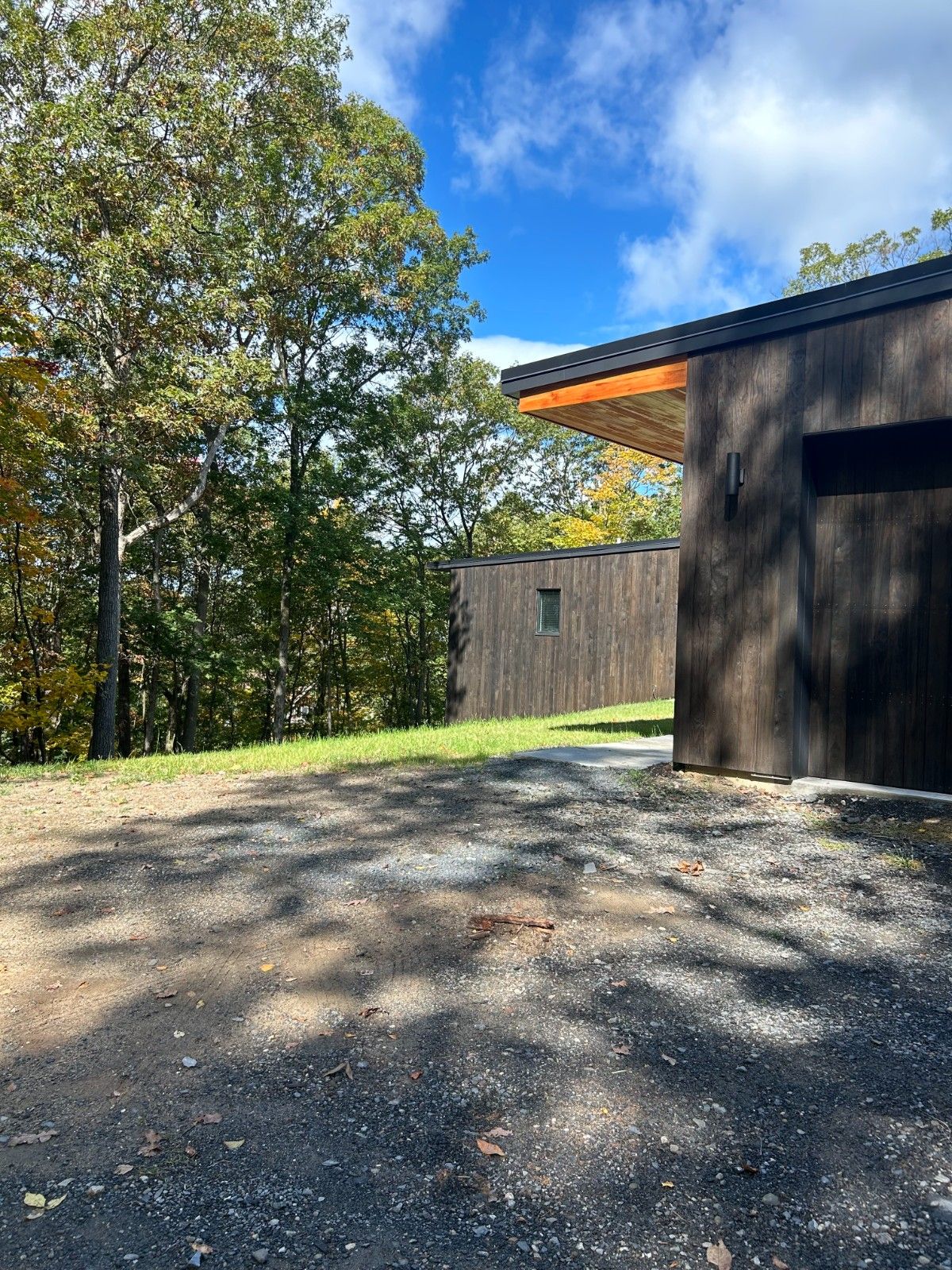 Exterior Wood Siding Staining on a contemporary home featuring dark vertical siding and large windows on a rocky landscape.