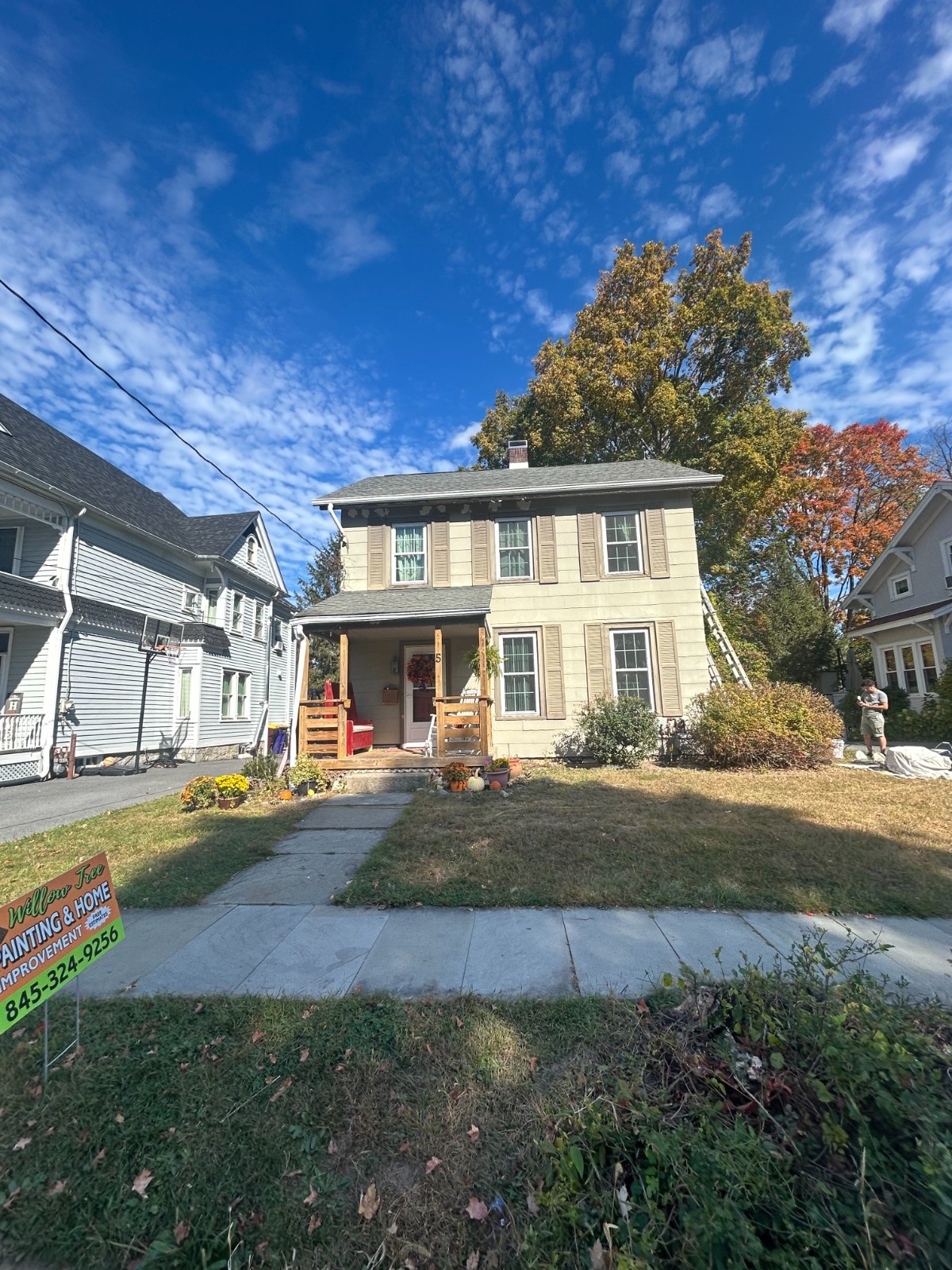 Professional Exterior House Painting of a two-story home in a light khaki color with contrasting brown shutters and trim.