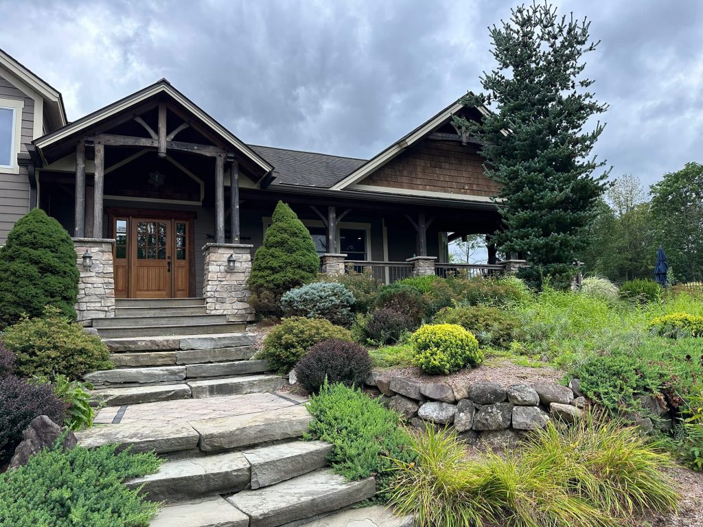 Rustic, high-end residential home with stone steps, wood siding, and timber accents, showing the type of quality exterior painting and staining projects handled by painters in Florida, NY