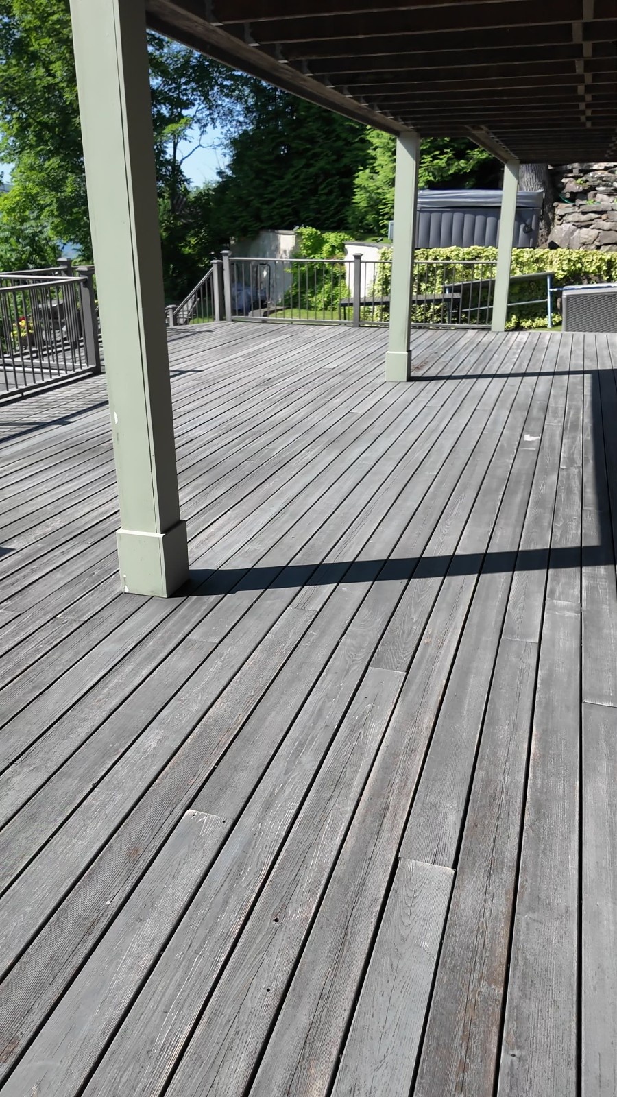 Deck Staining project highlighting the weathered grey finish on wood planks and painted structural posts.