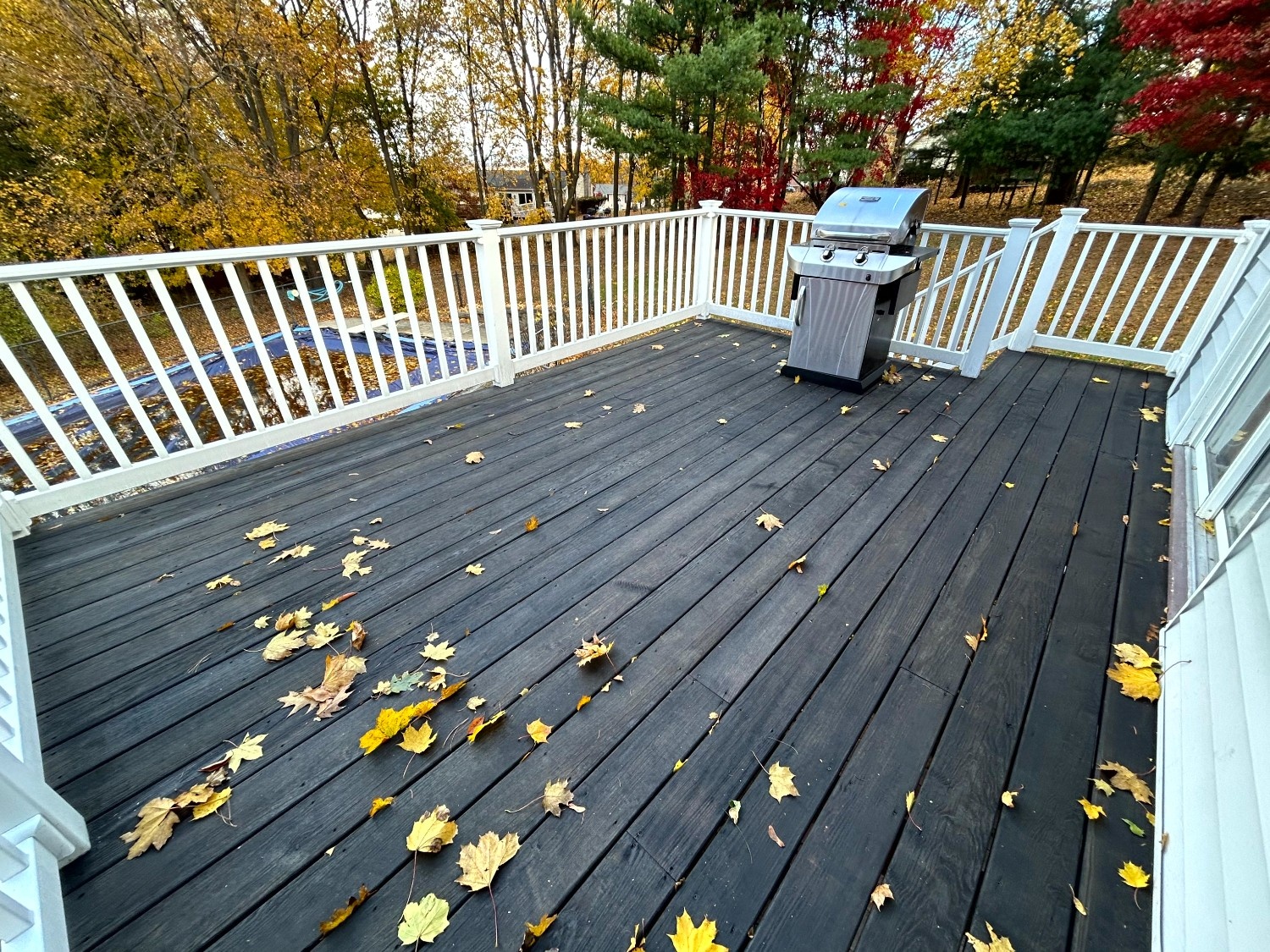 Professional Exterior Wood Finishing showcasing a modern dark deck stain and bright white painted railings.