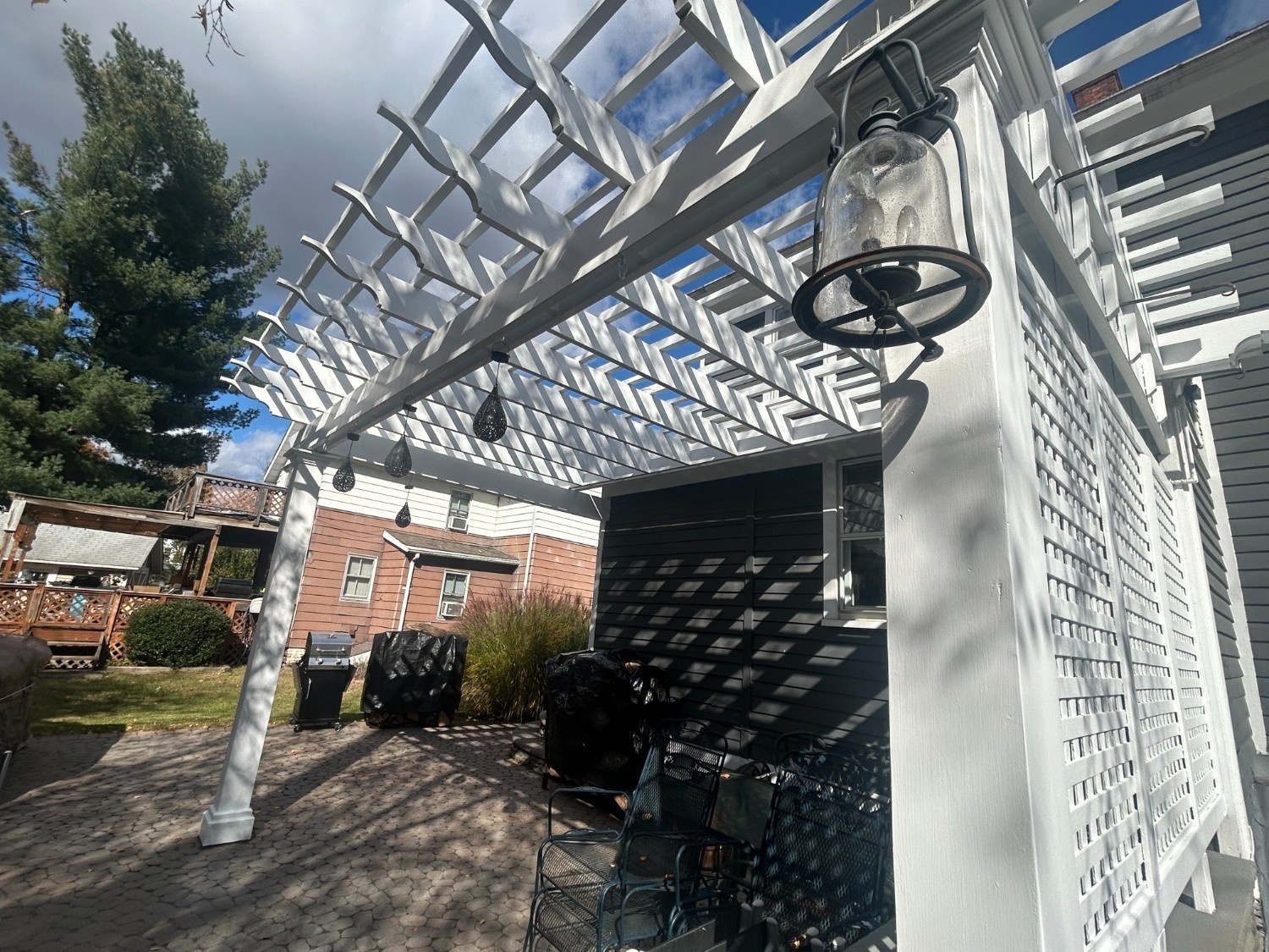 Professional Exterior Painting of an outdoor wood pergola and privacy lattice structure in a bright, clean white finish.