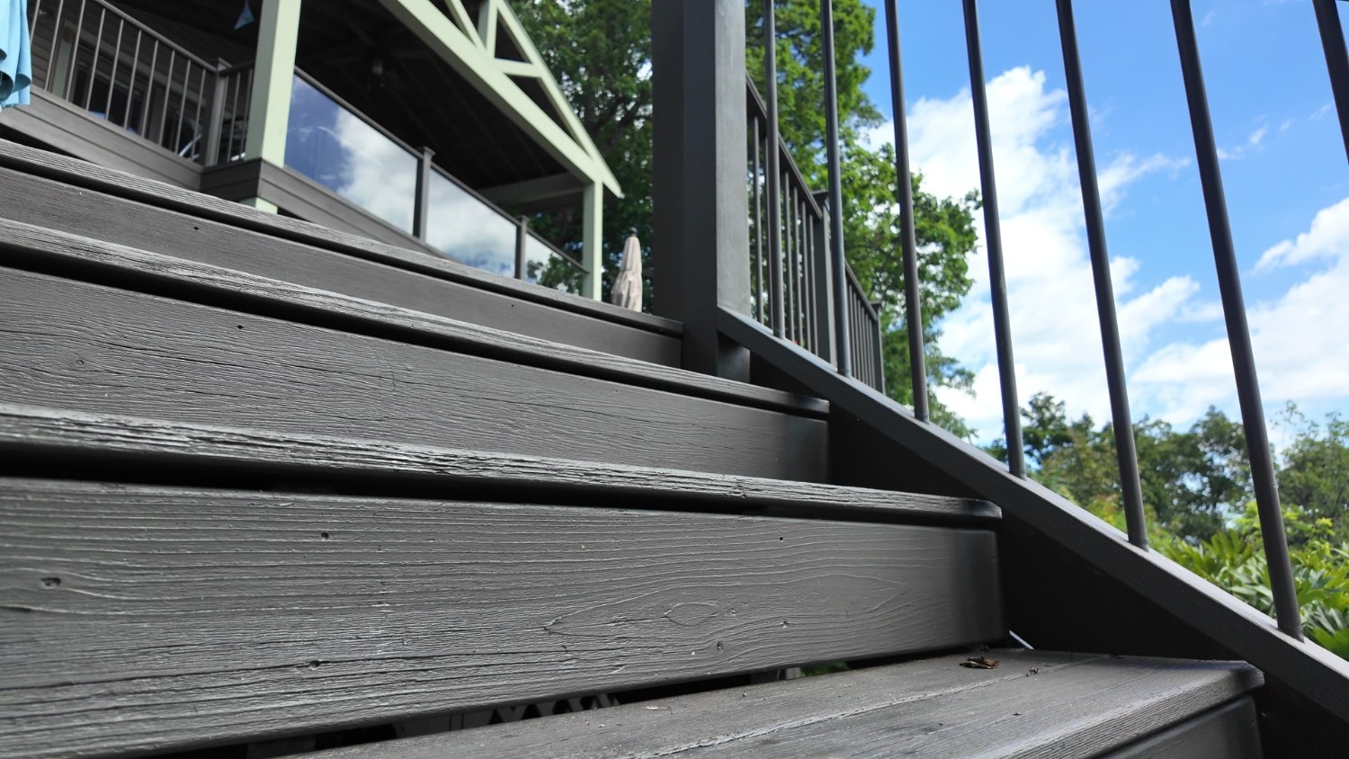 Professional Deck Staining and exterior wood finishing service showing deep grey color on deck stairs and railing.