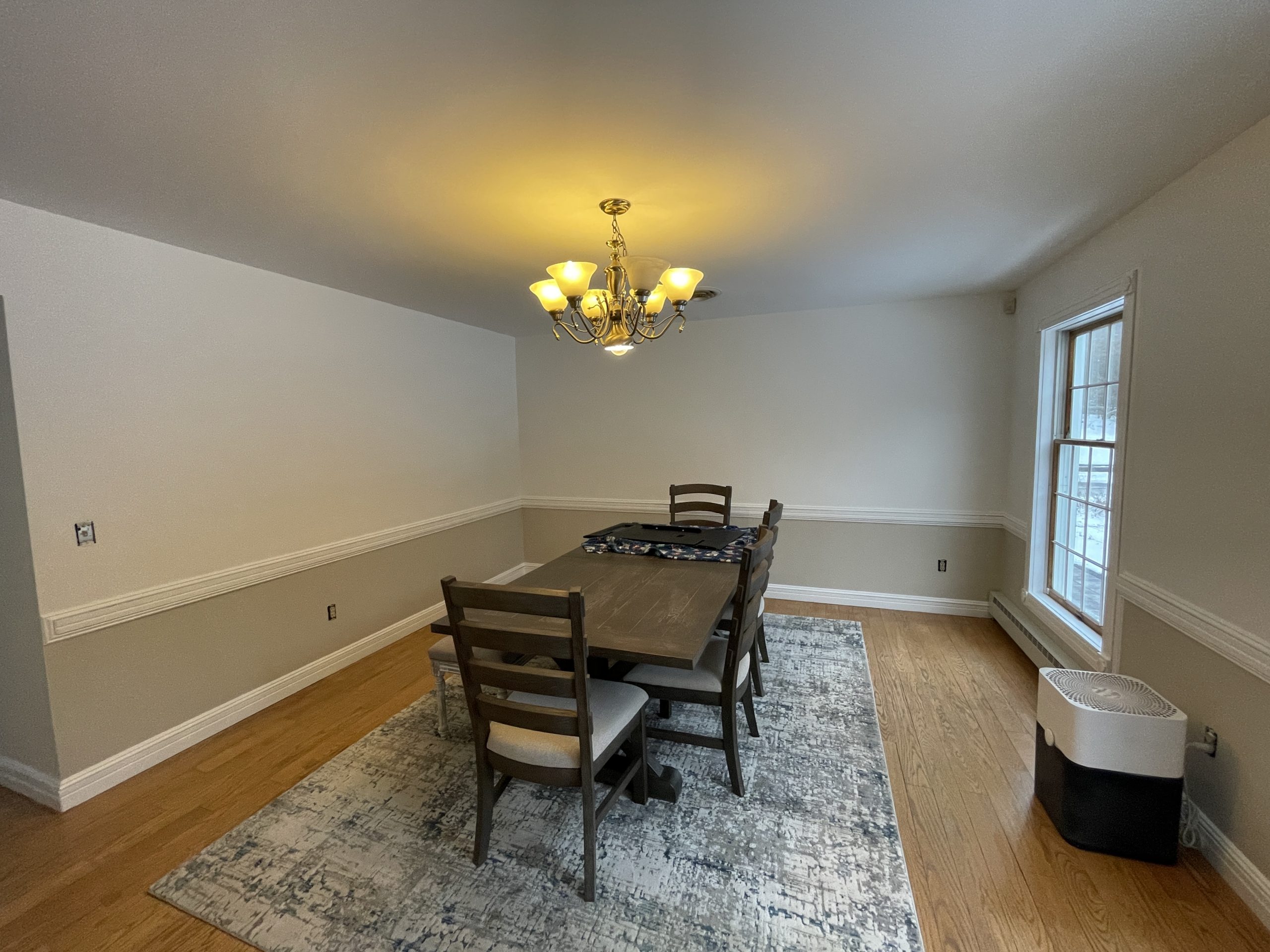 interior painting of a formal dining room featuring two-tone walls, white chair rail, and hardwood floors.