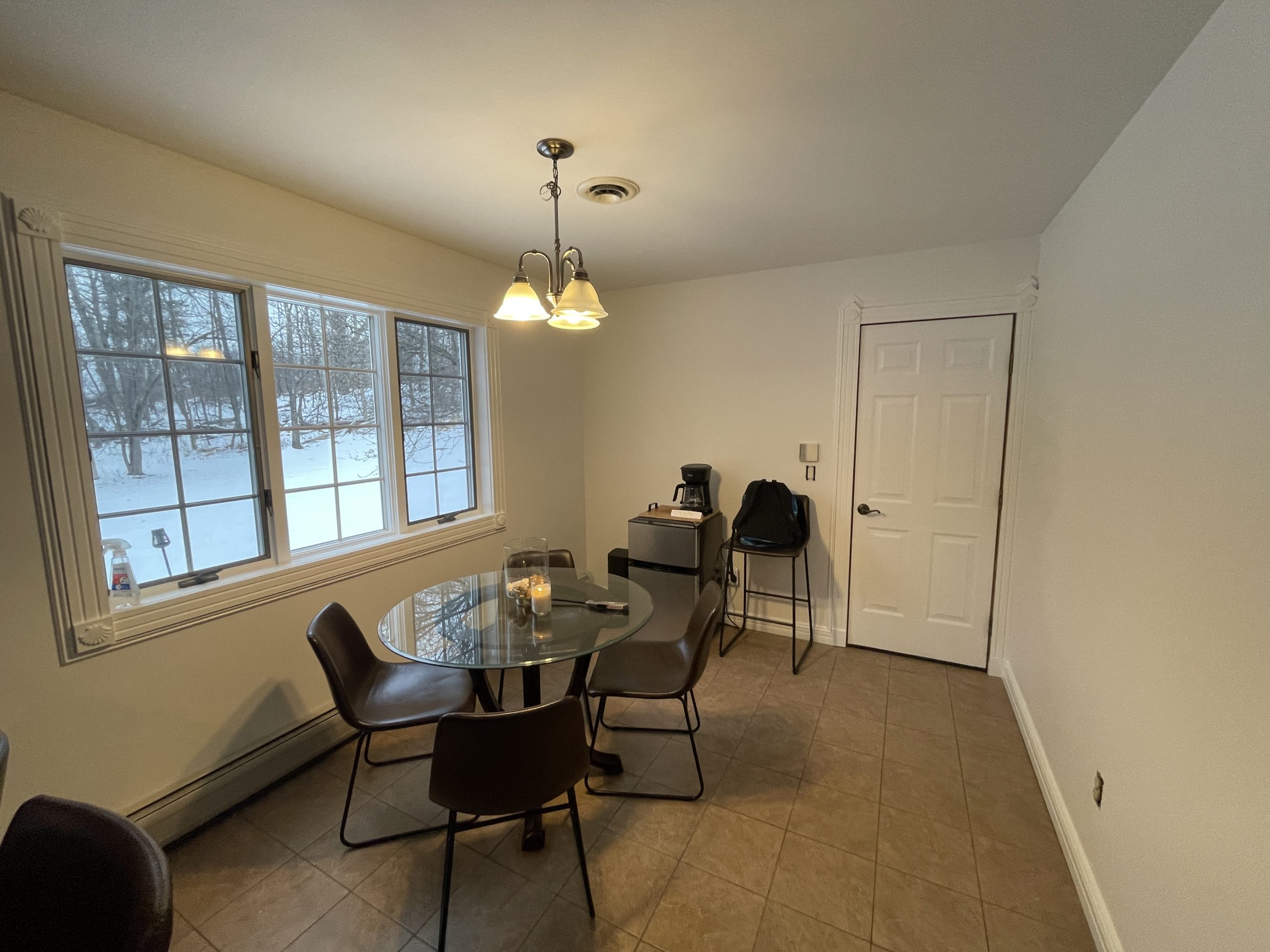 interior painting of a dining nook with crisp white walls, detailed white trim, and a tiled floor.