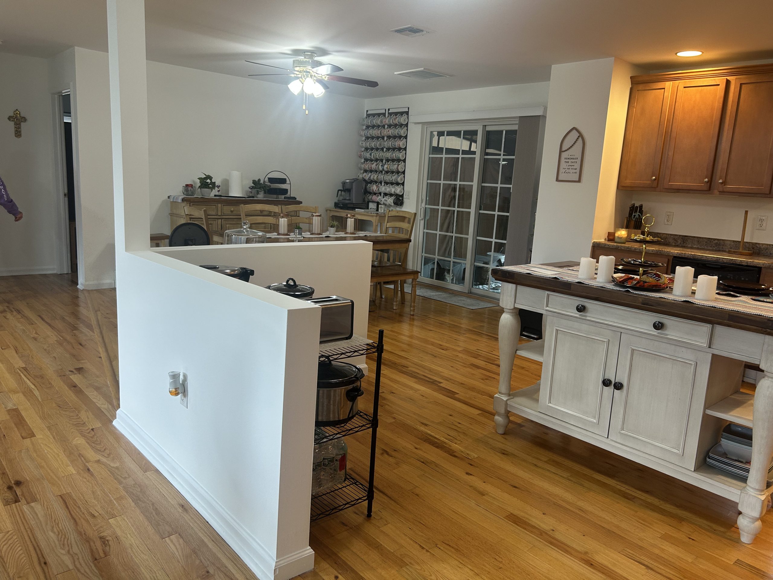 Interior painting of an open concept kitchen and dining room featuring bright white walls and polished hardwood floors.