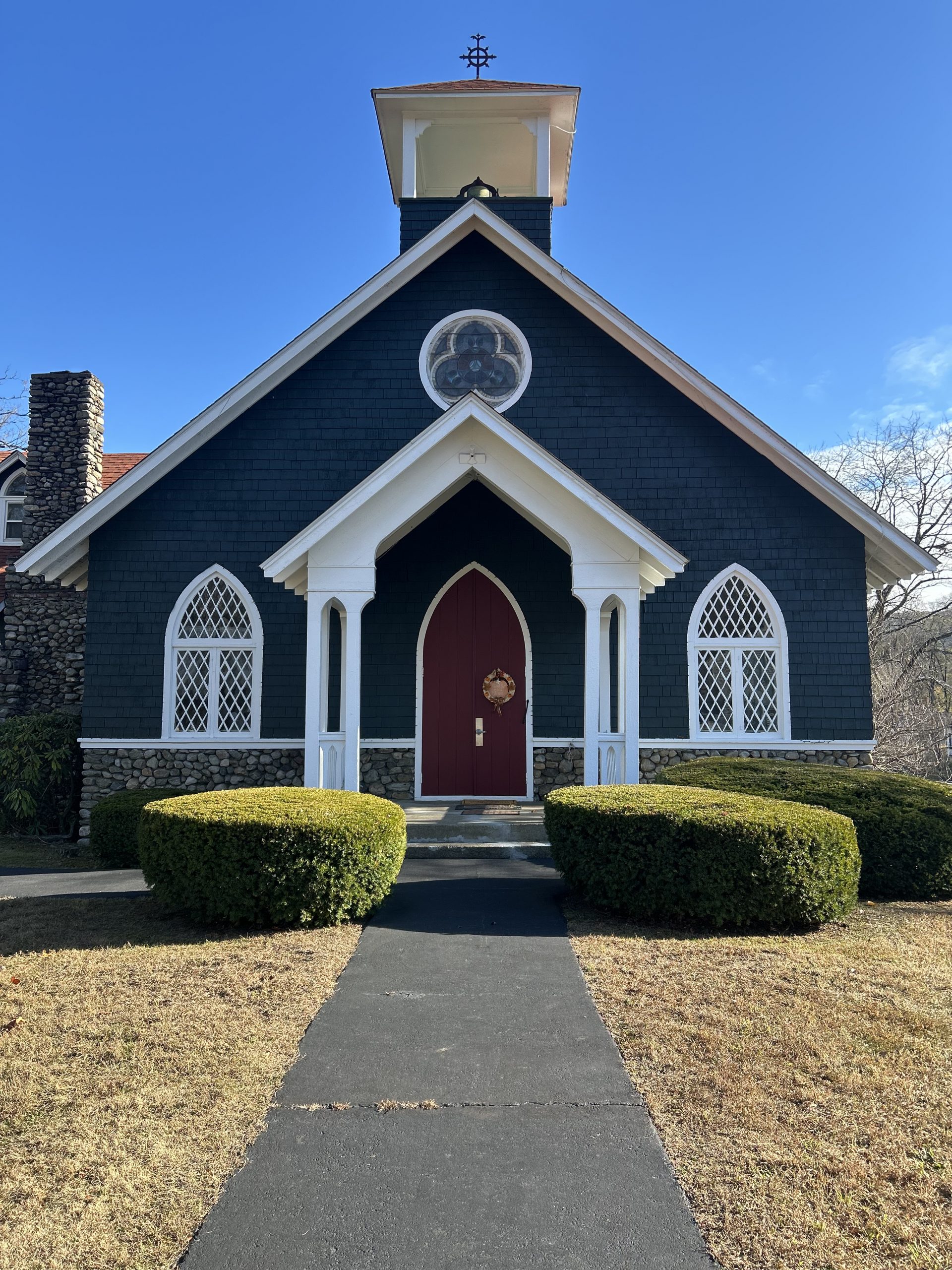 Historic Exterior Commercial Painting New York New Jersey on a chapel featuring dark siding, contrasting white trim, and a bright red door.