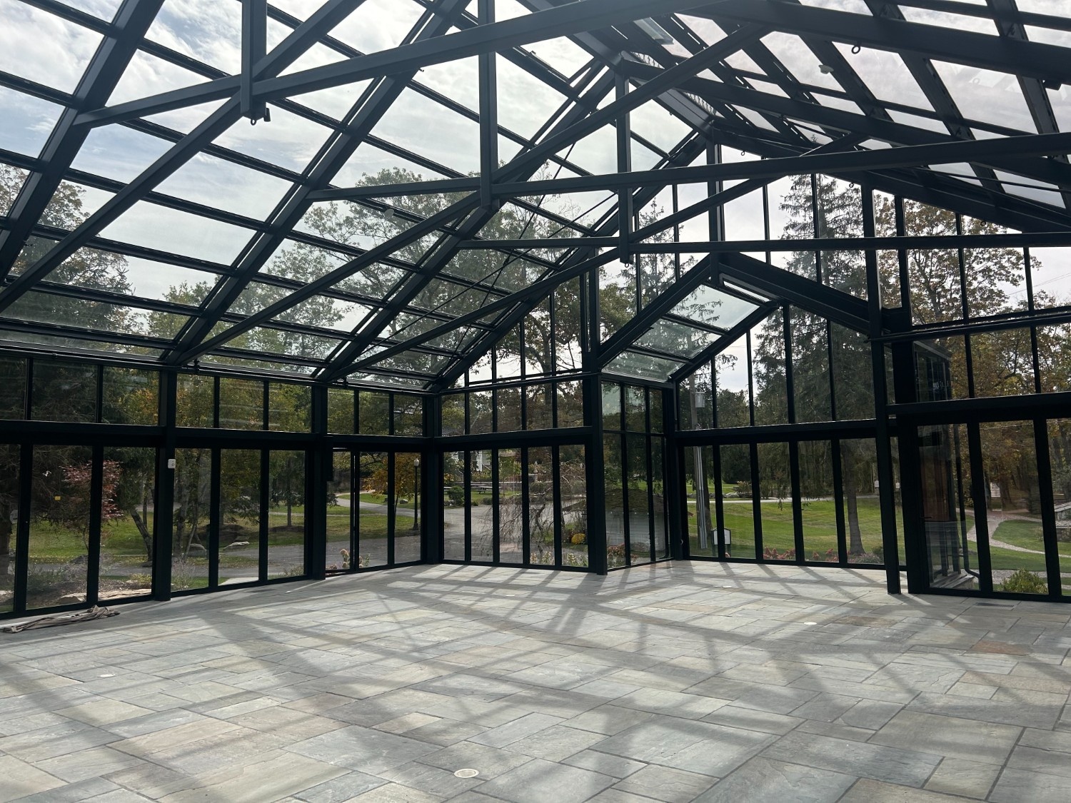 Structural Steel Commercial Painting New York New Jersey on a large high-end glass conservatory with dark metal framework and stone floors.