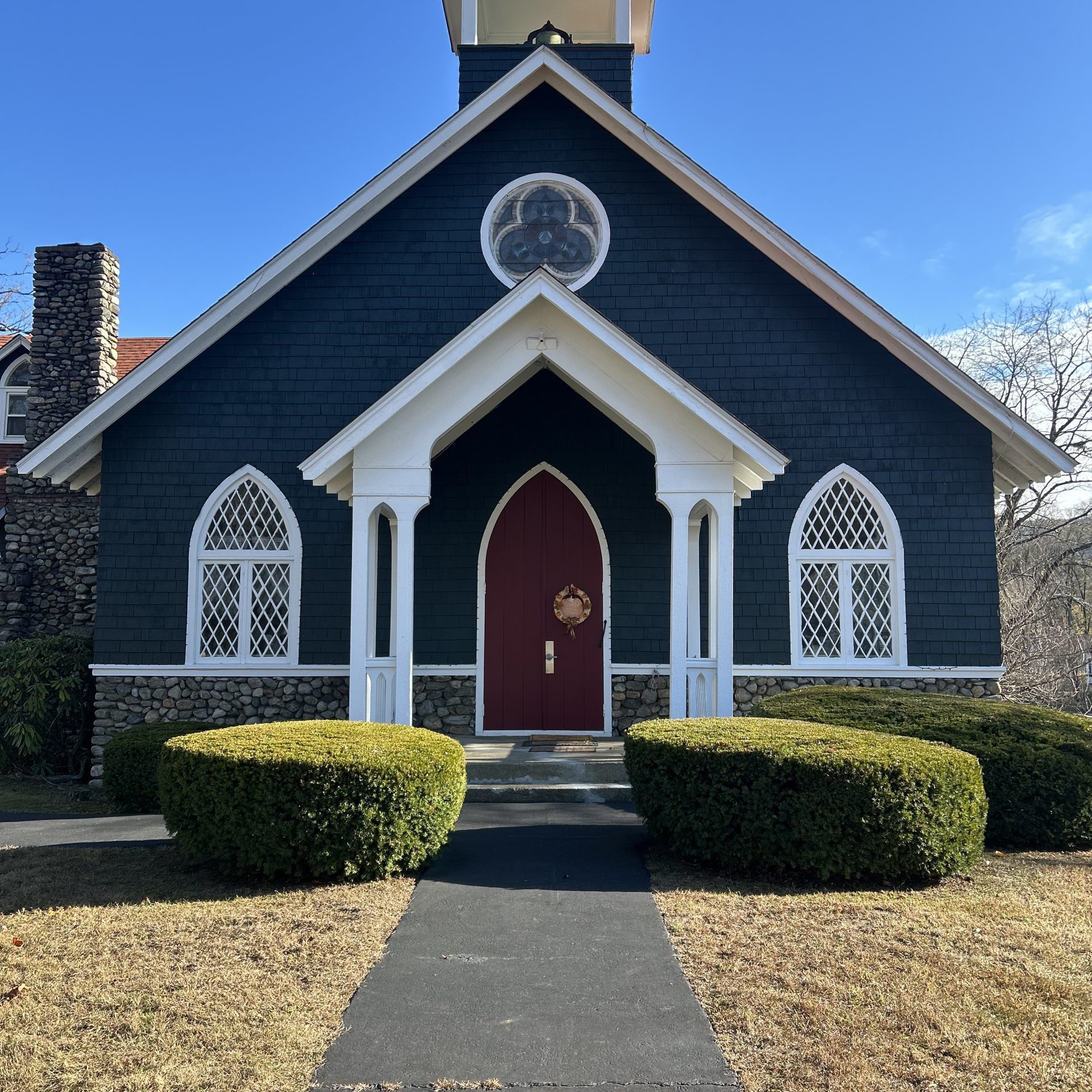 Historic Exterior Commercial Painting New York New Jersey on a chapel featuring dark siding, contrasting white trim, and a bright red door.