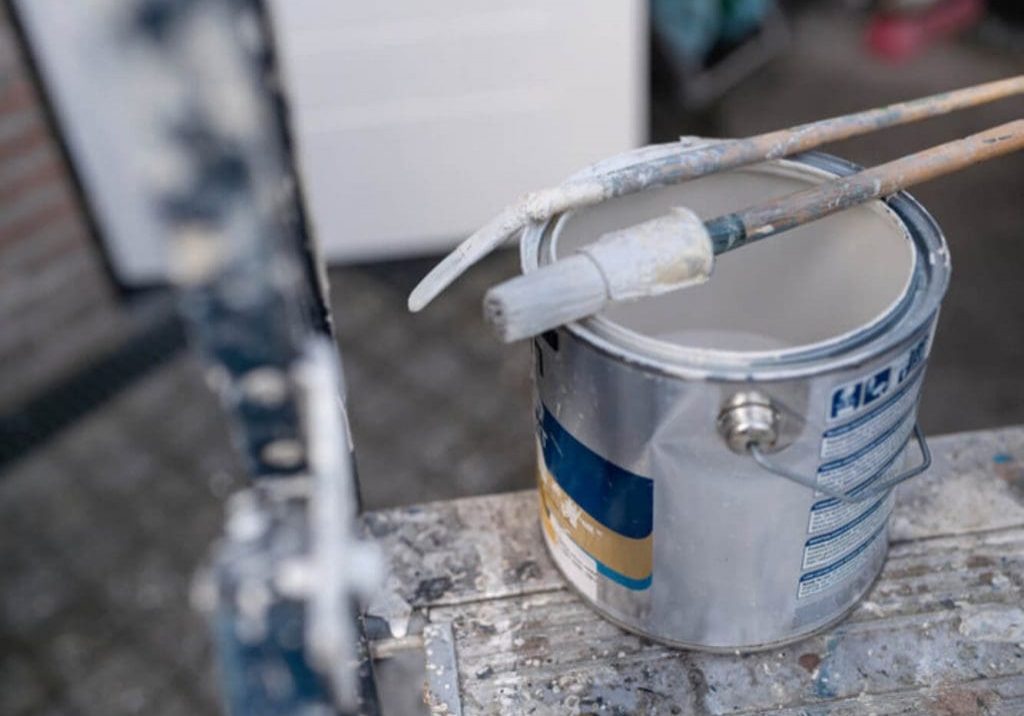 Paint can and brush on a ladder, representing the questions homeowners ask before hiring an exterior painting company.